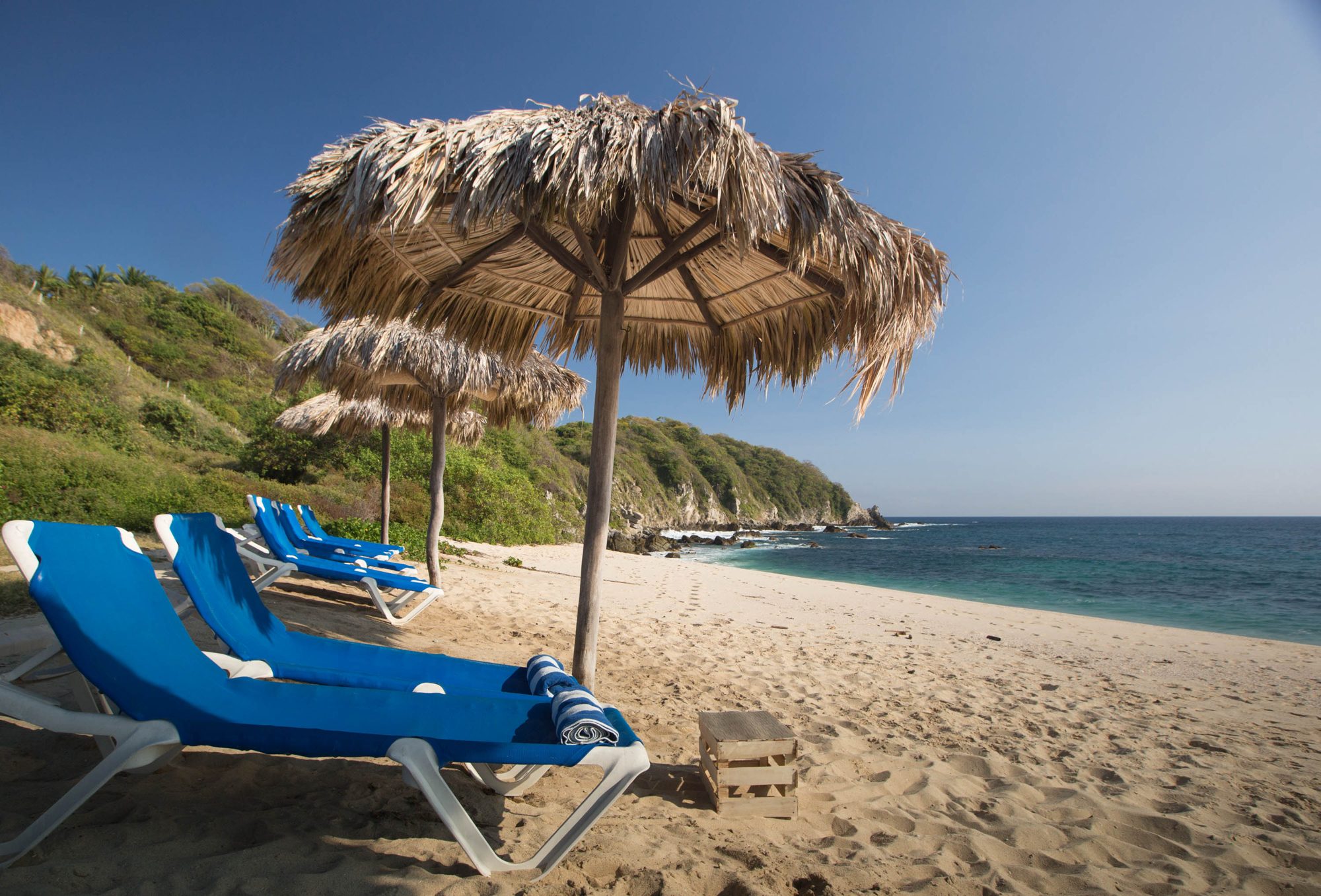 Un transat à l’ombre d’une palapa sur le sable blanc