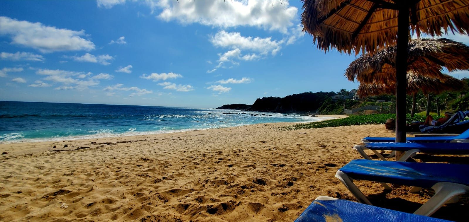 Transats sur le sable devant l’eau turquoise