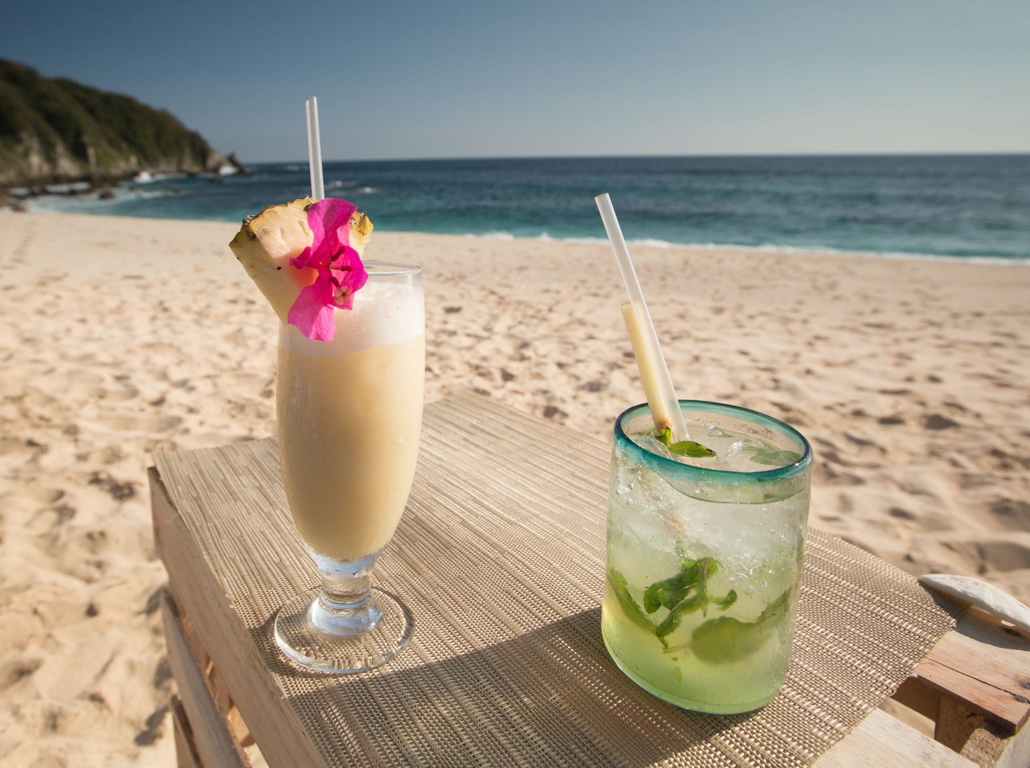 Une piña colada et une margarita sur une table dans le sable
