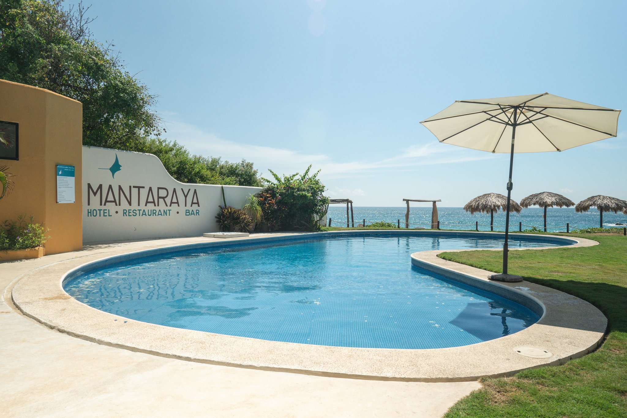 The Manta Raya pool with palapas and the Pacific beyond