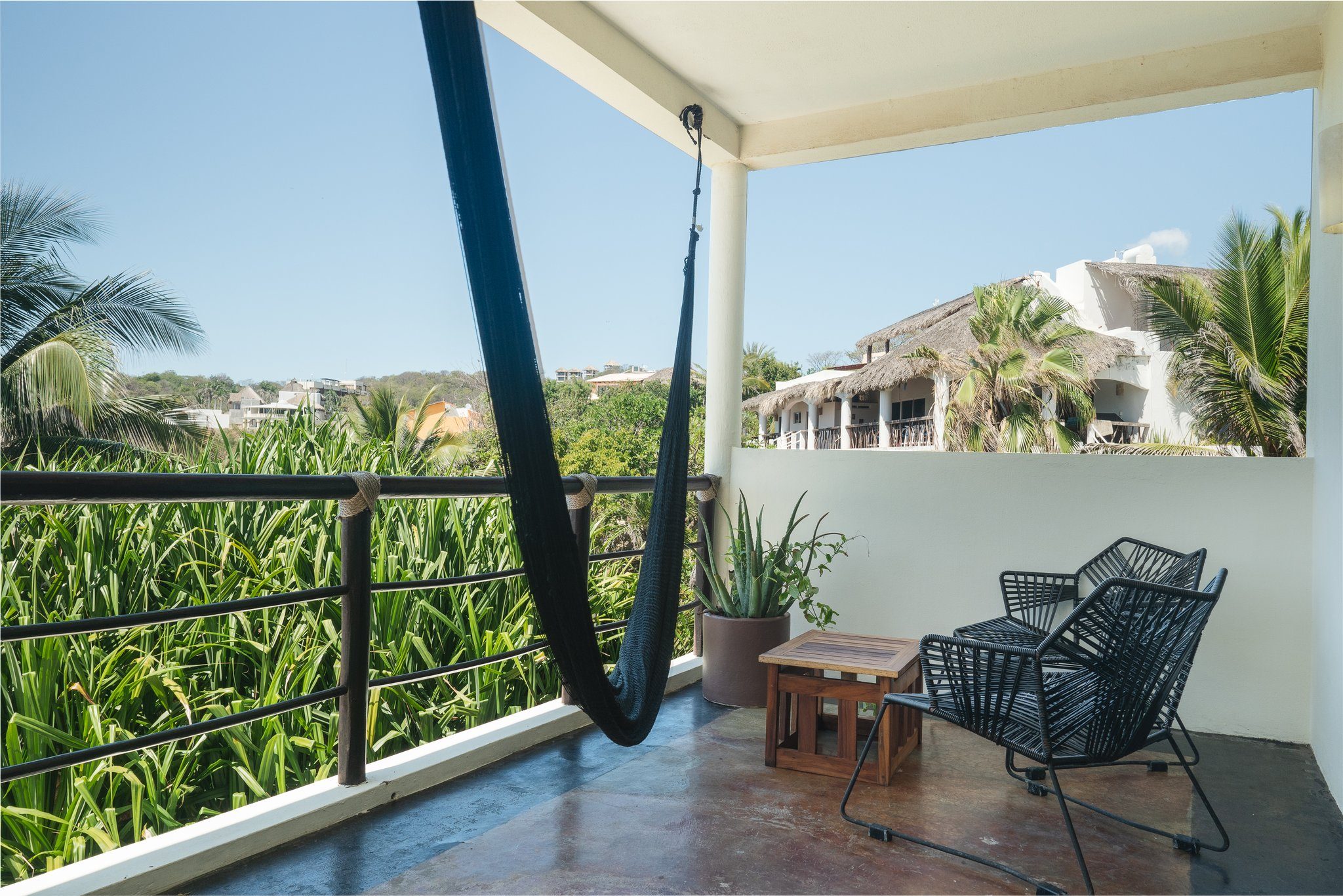 Terrasse mit Hängematte und Blick auf Palmen und Meer