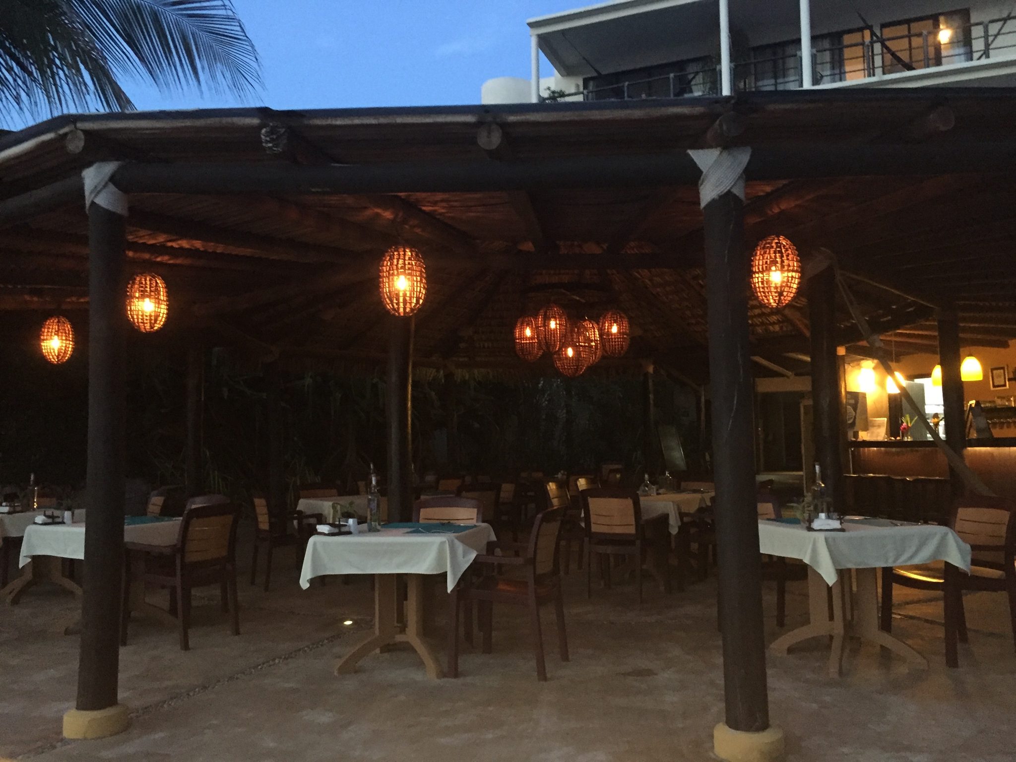 Le restaurant sous la palapa la nuit, éclairé par des lanternes suspendues
