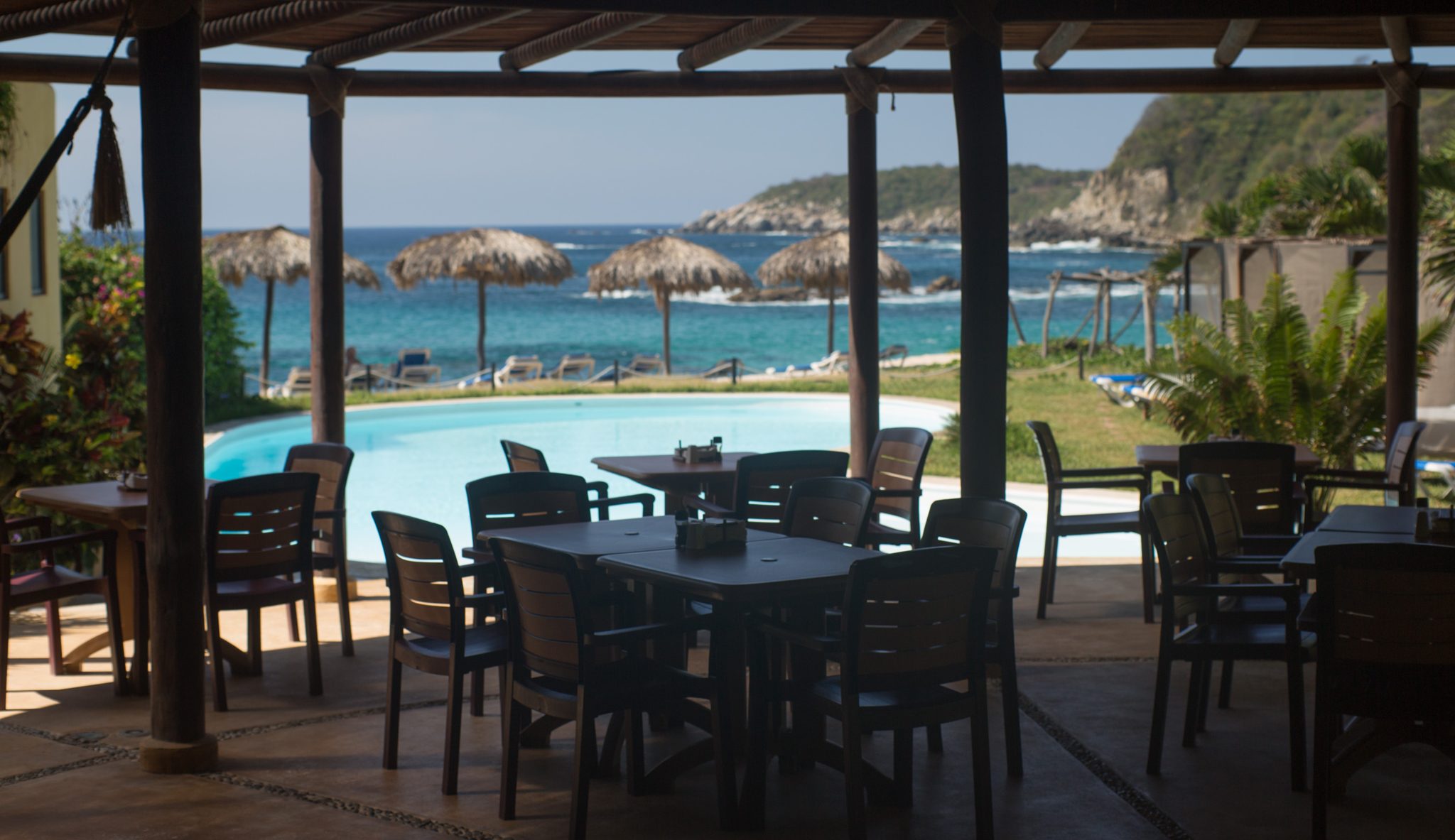 Le restaurant en plein air avec vue sur la piscine, les palapas et la baie