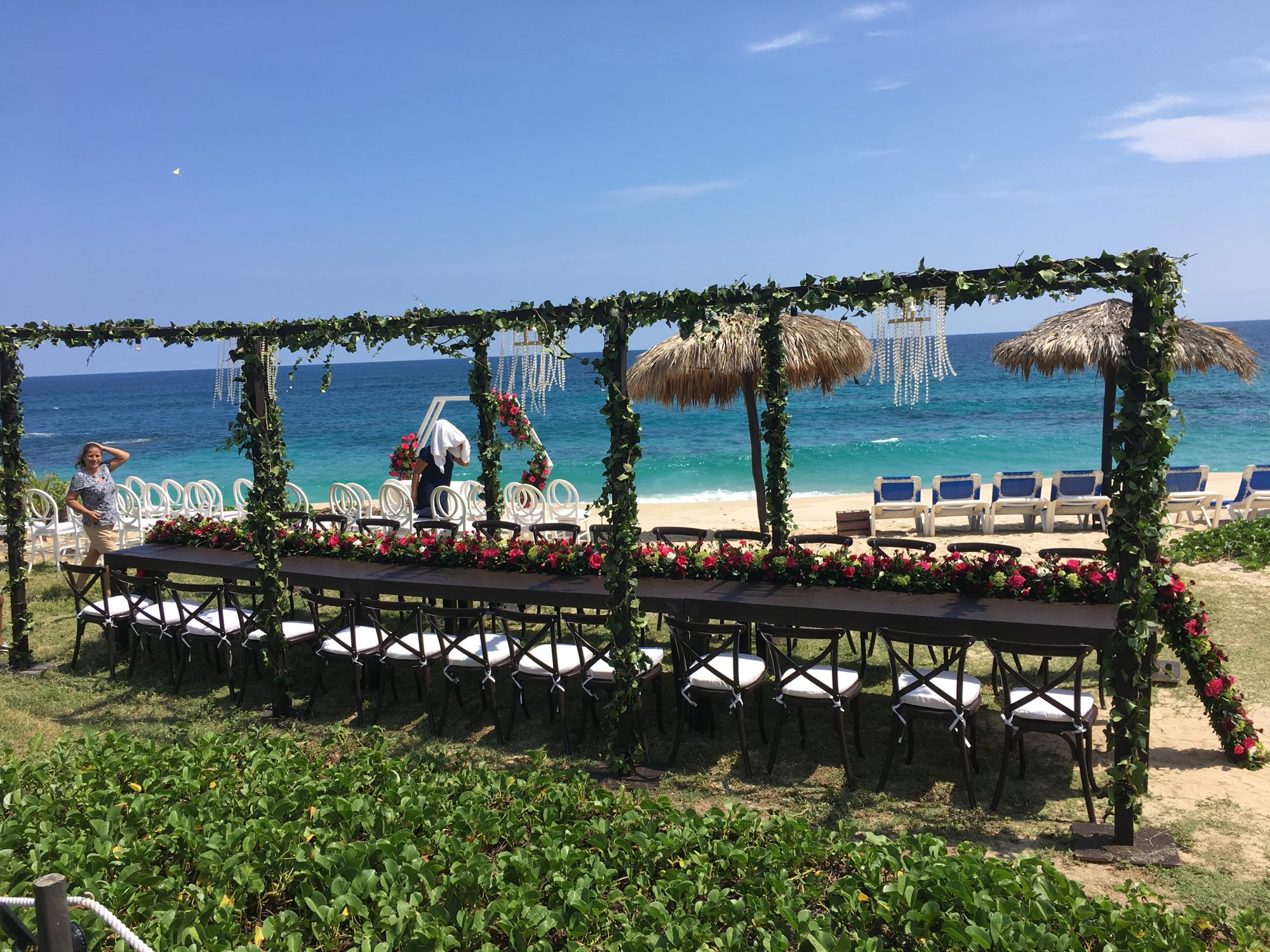 A wedding table under a floral arch on the beach