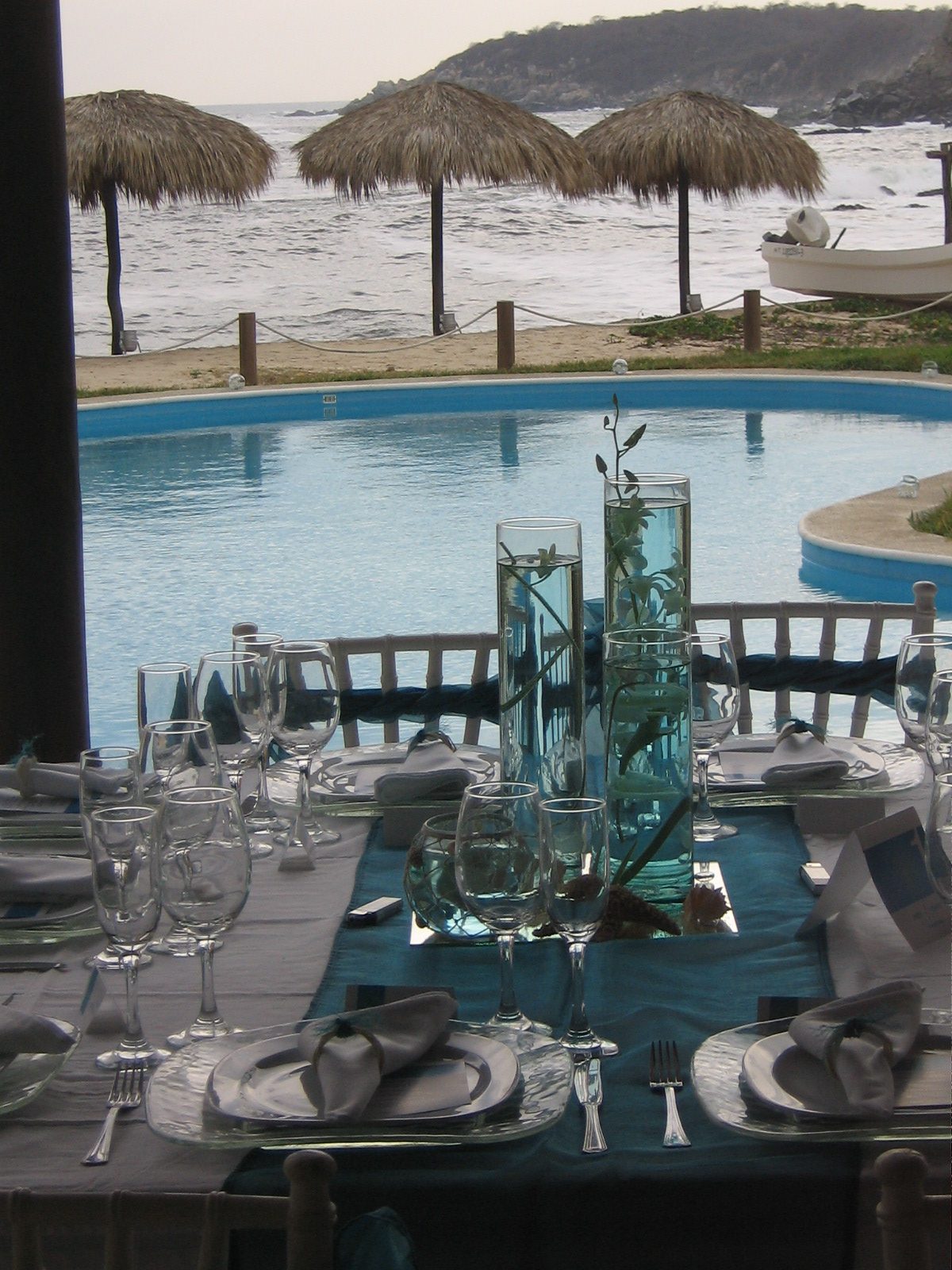 A poolside table set in turquoise with the beach beyond