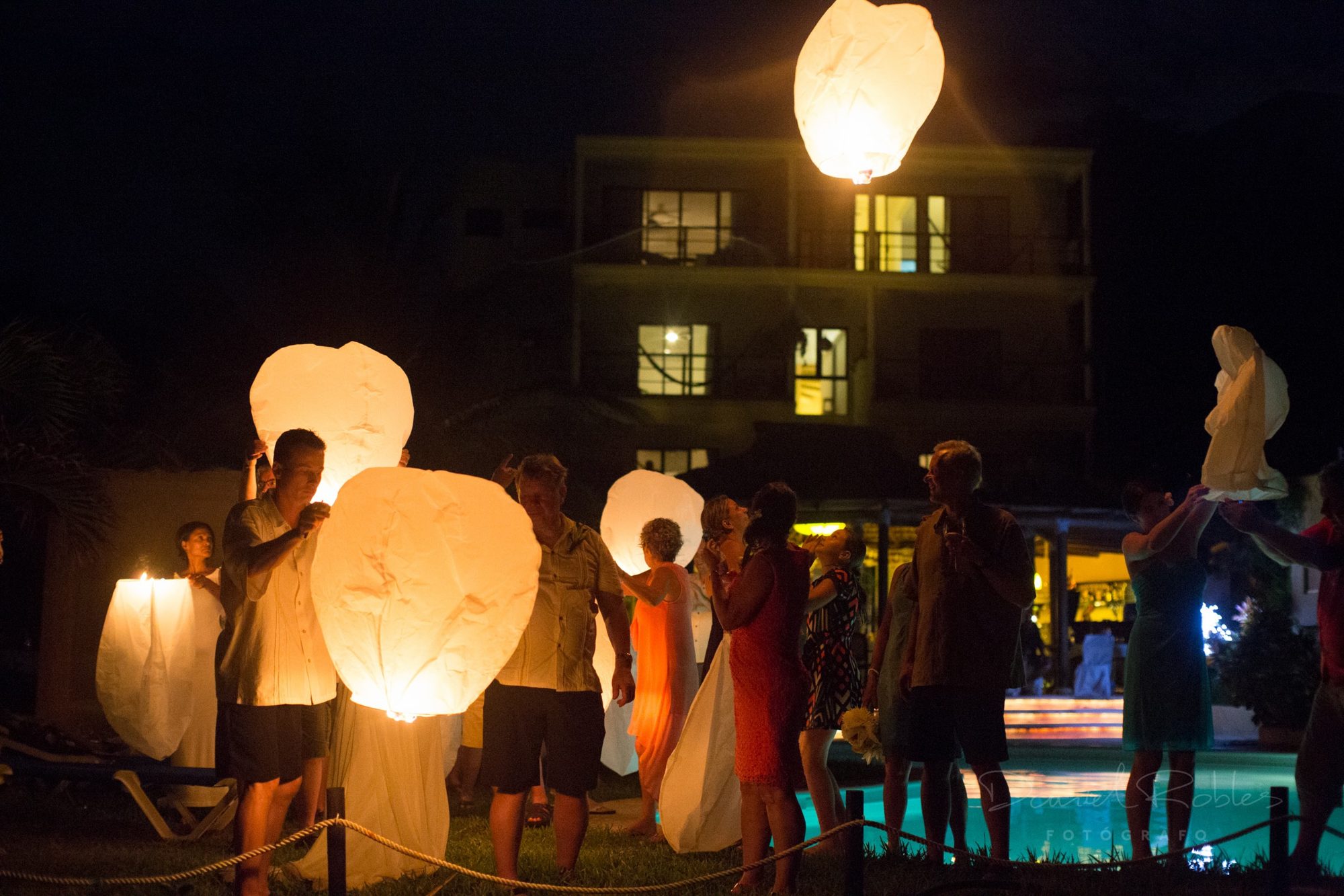 Guests releasing paper lanterns by the pool at night